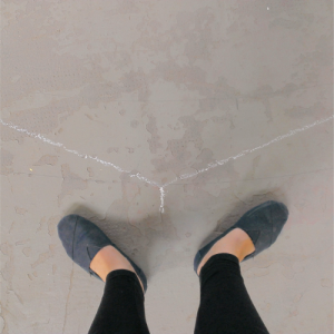 Mit Kreide ist ein stumpfer Winkel auf dem Steinboden angezeichnet. Ein Fußpaar ist im gleichen Winkel ausgerichtet.