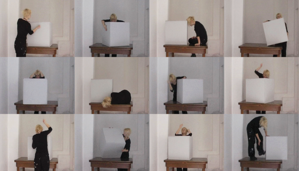 12 kleine Bilder zeigen eine junge Frau und einen weißen Holzwürfel mit 60 cm Kantenlänge. Sie schlägt und tritt in verschiedenen Positionen auf ihn ein.