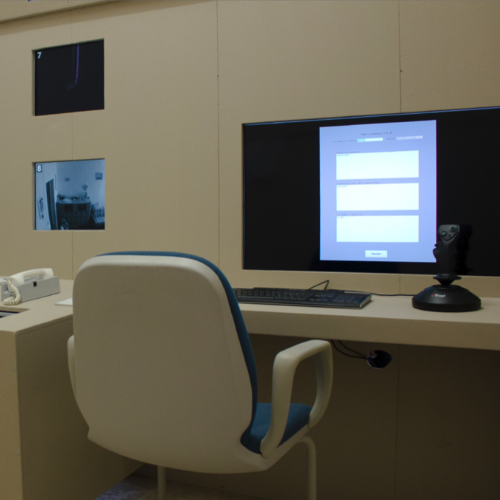 Ein Arbeitsplatz mit einer Tastatur, einem Joystick und einem fest in der Wand verbauten Monitor. Er zeigt eine Eingabemaske mit 3 Feldern.