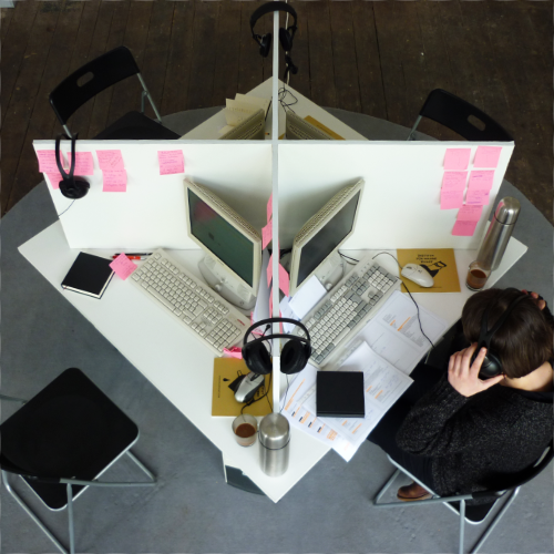 Ein quadratischer Tisch wird von diagonal aufgestellten Trennwänden in 4 Callcenter-Arbeitsplätze unterteilt.