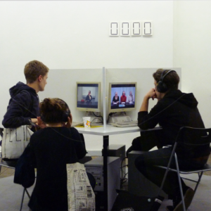 3 junge Leute schauen Videos an, die auf den Bildschirmen von separaten PC-Arbeitsplätzen laufen.