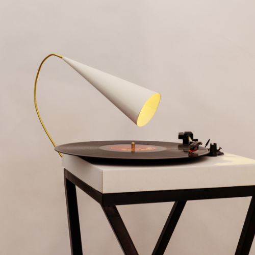 Ein minimalistisches Objekt mit Schallplatte, Tonarm und Trichter erinnert entfernt an ein Grammophon. Im Trichter leuchtet ein warmes Licht.
